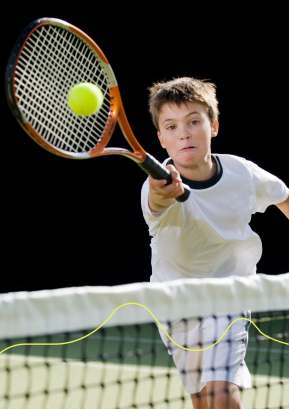 Jongen met tennisracket slaat op tennisbal