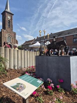 bronzen standbeeld paardenprocessie met infobordje en kerk van Gooik op de achtergrond