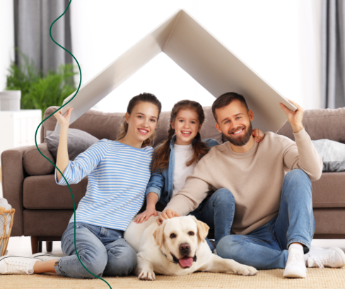 man, vrouw, kind en hond zitten op de grond voor de zetel en houden een dakje boven hun hoofd